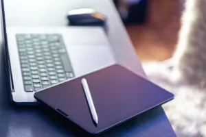 Tablette graphique posée sur un bureau avec un ordinateur portable, représentant la communication digitale